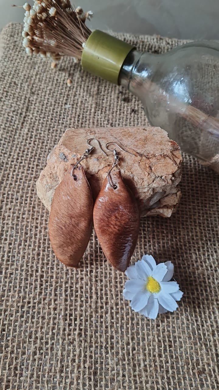 Brincos artesanais produzidos com sementes sobre tecido de juta